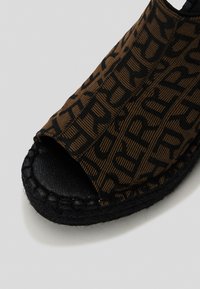 Infradito espadrille open-toe con tomaia in tessuto marrone con motivo testuale nero, suola in juta intrecciata nera e fodera interna testurizzata.