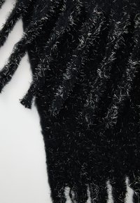 Tessuto nero con accenti in filo argentato, caratterizzato da una superficie testurizzata e pelosa e bordi sfrangiati che creano un design stratificato.