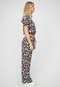 Set pohodlného oblečenia s leopardím vzorom, pozostávajúci z krátkeho topu s krátkymi rukávmi a voľnými nohavicami širokého strihu, vyrobený z mäkkého materiálu v odtieňoch ružovej a čiernej.