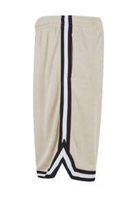 Beige mesh shorts med sort og hvid side-striber, en snoretræk ved taljen og en skrå kant for ekstra stil og ventilation.