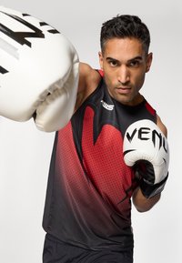 Sporty black and red sleeveless shirt with a geometric pattern, paired with white boxing gloves featuring black text and accents.