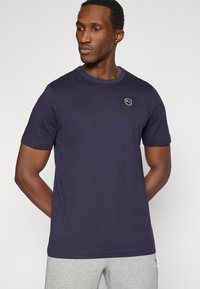 Μπλούζα κοντομάνικη σε ναυτικό μπλε χρώμα, κατασκευασμένη από βαμβάκι, με στρογγυλή λαιμόκοψη και μικρό λογότυπο στο στήθος. Διαθέτει μονόχρωμο σχέδιο και απαλή υφή.