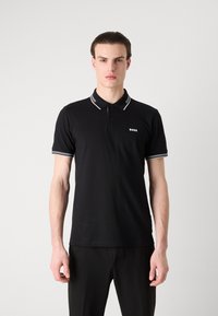Čierne polo tričko s bielym prúžkovaným golierom a manžetami, s dvojzápadkovým zapínaním a malým logom na hrudi. Hladká textúra tkaniny.