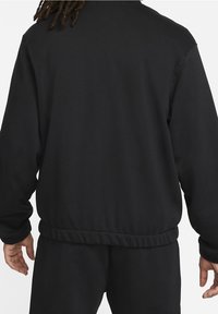 Svart hoodie med rund halsringning, ribbade ärmslut och elastisk midja, tillverkad av ett mjukt och slätt tyg. Inga synliga mönster.