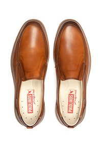 Zapatos de cuero marrón tipo mocasín con una forma redondeada, costuras sutiles, plantillas color crema y un logo. Textura suave, sin cordones.