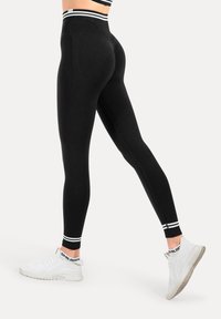 Zwarte leggings met een hoge tailleband en witte gestreepte accenten. Gemaakt van een rekbaar materiaal, een aansluitend ontwerp, geschikt voor actieve kleding.