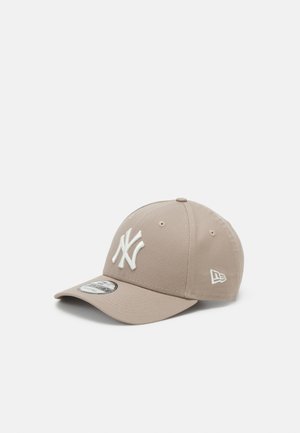 Beżowa czapka z daszkiem z haftowanym białym logo New York Yankees z przodu oraz logo New Era z boku, z zakrzywionym daszkiem.