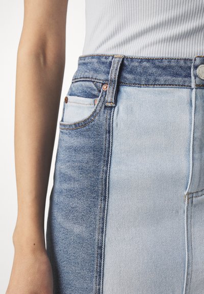 Light blue and dark blue denim skirt with a high waist, featuring contrasting fabric sections, a front pocket, and copper button accents.
