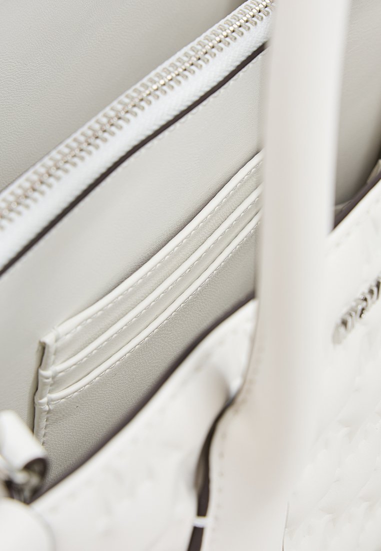 Weiße Handtasche mit strukturiertem Finish, ausgestattet mit einem Reißverschlussfach und Kartenfächern im Inneren. Glattes Leder, minimalistisches Design.