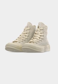 Αθλητικά παπούτσια με ψηλή φτέρνα, κατασκευασμένα από υλικό μπεζ με υφή, με κορδόνια σε κοντινή απόχρωση και λαστιχένιες σόλες. Διαθέτουν σόλα με σχέδιο και στρογγυλεμένη μύτη.