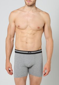 Grå bomullshorts med svart midjeband med vita ränder och logotyp, designade för en åtsittande passform. Slät textur och medellång klippning.