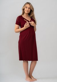 Těhotenské šaty v burgundské barvě, krátké rukávy, design s V výstřihem a překříženým panelem, měkká tkanina, délka po kolena, vroubkovaný lem.