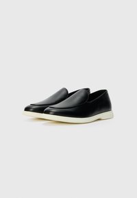 Fekete bőr slip-on cipők sima felülettel, lekerekített orral és fehér gumitalppal. Minimalista dizájn, látható fém- vagy mintázat nélkül.