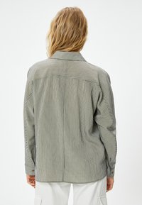 Gestreiftes Hemd mit langen Ärmeln und Kragen in Grün und Creme. Weicher Stoff und lockere Passform mit klassischem Rückenausschnitt.