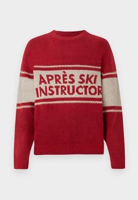 Maglione rosso con collo a giro, caratterizzato da una banda beige con la scritta "APRÈS SKI INSTRUCTOR" e un motivo a maglia testurizzata. Polsini e orlo a coste.