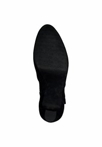 Semelle de chaussure noire avec le nom de marque "Tamaris" en relief, présentant une texture lisse et une forme effilée, conçue pour le confort et l'adhérence.