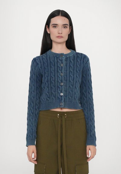 Cardigan en tricot bleu à cable avec des manches longues, un col rond et des boutons à l'avant. Design court avec des poignets et un ourlet côtelé.
