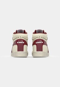 High-top sneakers in cream and burgundy leather with textured accents, featuring decorative studs and a logo on the sides and heel.