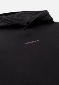 Schwarzer Hoodie mit einer vorderen Kängurutasche, weitem Ausschnitt und "TOMORROWLAND" in helllila auf der Brust gedruckt. Weiche Textur.