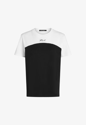 Korte mouw t-shirt met een witte bovensectie en een zwarte ondersectie, met een gebogen ontwerp en "Karl" geborduurd in het zwart.