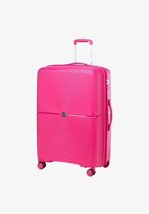 Valise rigide rose avec un motif de vagues, poignée télescopique, poignée latérale et quatre roues pour la mobilité. Logo de la marque affiché.