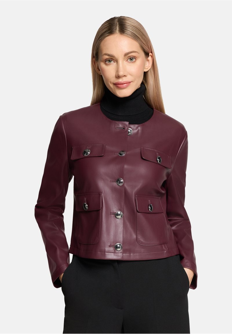 Bordowa skórzana kurtka z zaokrąglonym kołnierzem, zapinana na guziki z przodu, wyposażona w dwie kieszenie na piersi. Gładka faktura i dopasowany krój.