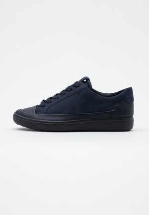 Baskets basses noires avec lacets à l’avant et semelle texturée, vues de profil sur fond blanc uni.