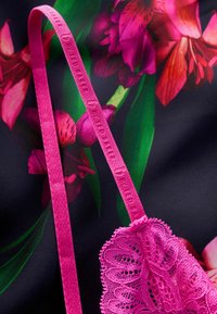 Roze kanten beha met bloemenstrapdetail, voorzien van een delicate geschulpte rand en een gladde stofachtergrond met kleurrijke bloemenpatronen.