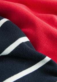 Baumwollstoff in Rot und Marineblau, mit horizontalen weißen Streifen. Nahaufnahme zeigt die weiche Textur und den mehrlagigen Fall.