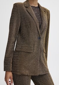 Brauner metallic Blazer mit einem einzigen Knopf, Reverskragen und zwei seitlichen Taschen. Strukturierter Stoff mit schimmerndem Finish.