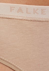 Hellbeiger elastischer Bund mit eingeprägtem "FALKE"-Logo; weiche, gerippte Textur; nahtloses Design für Komfort und Flexibilität.