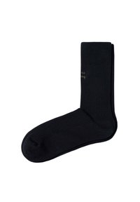 Un par de calcetines negros de canalé, doblados cuidadosamente con un texto sutil bordado cerca del puño superior sobre un fondo blanco.