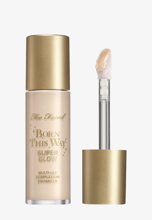 Born This Way Super Glow huidverbeteraar in een matglazen flesje met een metalen gouden dop; voorzien van een doorzichtige applicator met een crèmeproduct.