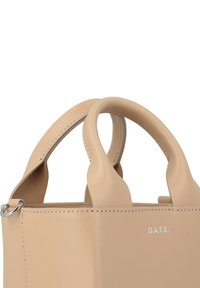 Bolso estructurado beige hecho de piel suave. Cuenta con dos asas cortas y herrajes de plata con el logotipo de la marca grabado en el lateral.