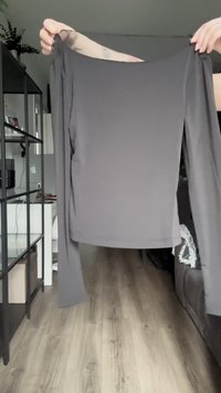 Dlhý rukáv, tmavosivý top vyrobený z mäkkej, elastickej látky. Má široký výstrih a priliehavé telo s rovnými rukávmi.