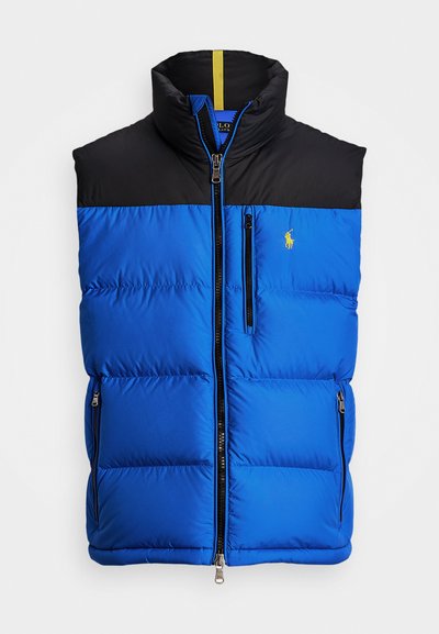 Colete acolchoado azul isolado com uma parte superior preta, colarinho alto, fecho frontal, dois bolsos laterais e um pequeno logótipo amarelo no peito.