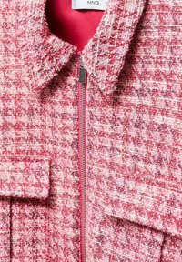 Veste en tweed rose et blanc avec col, fermeture éclair métallique et deux poches à rabat à l'avant.