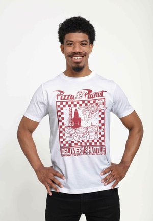 White cotton t-shirt featuring a red graphic print with a checkered border, alien characters, and "Pizza Planet Delivery Shuttle" text.