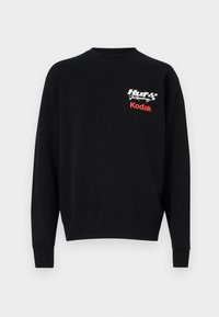 Sort sweatshirt med lange ærmer, rund hals, med "Huf Racing" i hvid og "Kodak" i rød på forsiden. Blød stoftekstur.