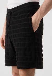 Zwarte shorts met een gestructureerd, gestreept patroon, voorzien van een elastische tailleband, trekkkoord en zijzakken. Zacht materiaal met HUGO-merk.