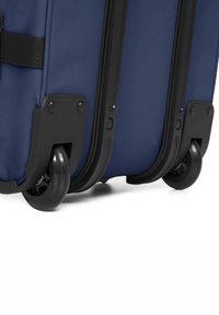 Valigia a rotelle blu navy con corpo in tessuto resistente, eleganti rifiniture nere e due grandi ruote nere per la mobilità.