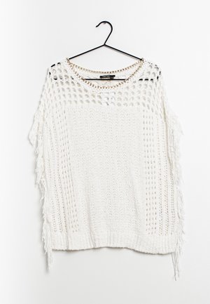 Maglione bianco lavorato a maglia con design a rete aperta. Presenta dettagli con frange lungo i lati e un colletto decorato con catene. Appeso a un gancio nero.