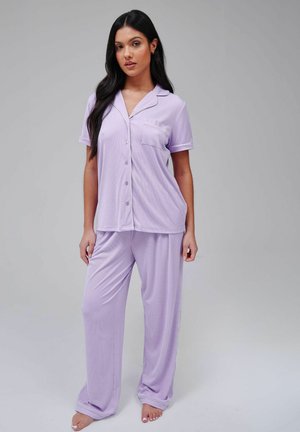 Lyselilla pyjamasæt bestående af en kortærmet skjorte med knapper og en lomme samt lange bukser. Fremstillet af blødt, let stof med ribbet tekstur.