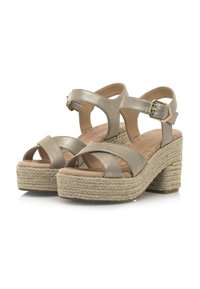 Sandales à plateforme en or métallique avec des brides croisées, boucle réglable à la cheville et talon en jute tissé pour plus de texture et de stabilité.