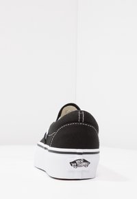 Sneaker Vans neri vista da dietro, con cuciture bianche, suola bianca spessa e logo "Vans Off The Wall" sul tallone.