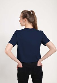 T-shirt blu navy a maniche corte con scollo rotondo, texture liscia e fitting rilassato, mostrato da dietro su uno sfondo semplice.