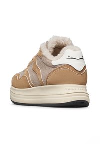 Sneaker in suede beige e tan con rivestimento morbido, accento bianco sul tallone e suola in gomma texturizzata. Elementi di design curvi distintivi.