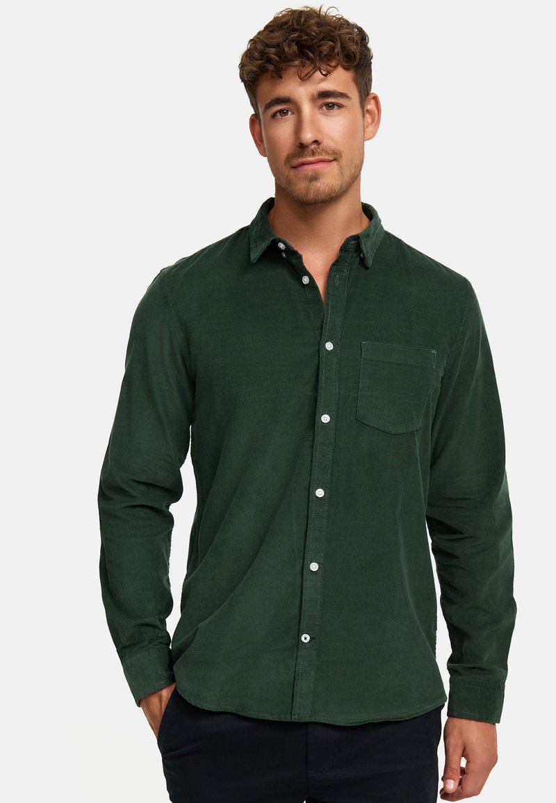 Dunkelgrünes Cordhemd mit langen Ärmeln, einem Button-Down-Kragen und einer Brusttasche. Verfügt über weiße Knöpfe und eine strukturierte Oberfläche.