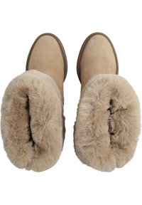 Bottines en suède beige avec doublure en fausse fourrure douce. Forme arrondie, coutures surpiquées et semelle en caoutchouc pour une meilleure adhérence.