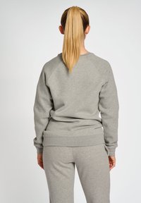 Szara bluza z raglanowymi rękawami, miękka w dotyku, z prążkowanym dołem i mankietami, w zestawie z pasującymi spodniami dresowymi. Widok z tyłu, bez wyraźnych detali.